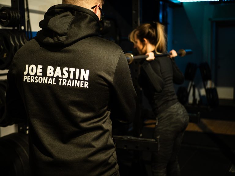 Joe Bastin Personal Trainer helping client with squats in a Basingstoke gym