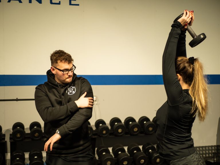 Fitness coach Basingstoke working with a client using weights